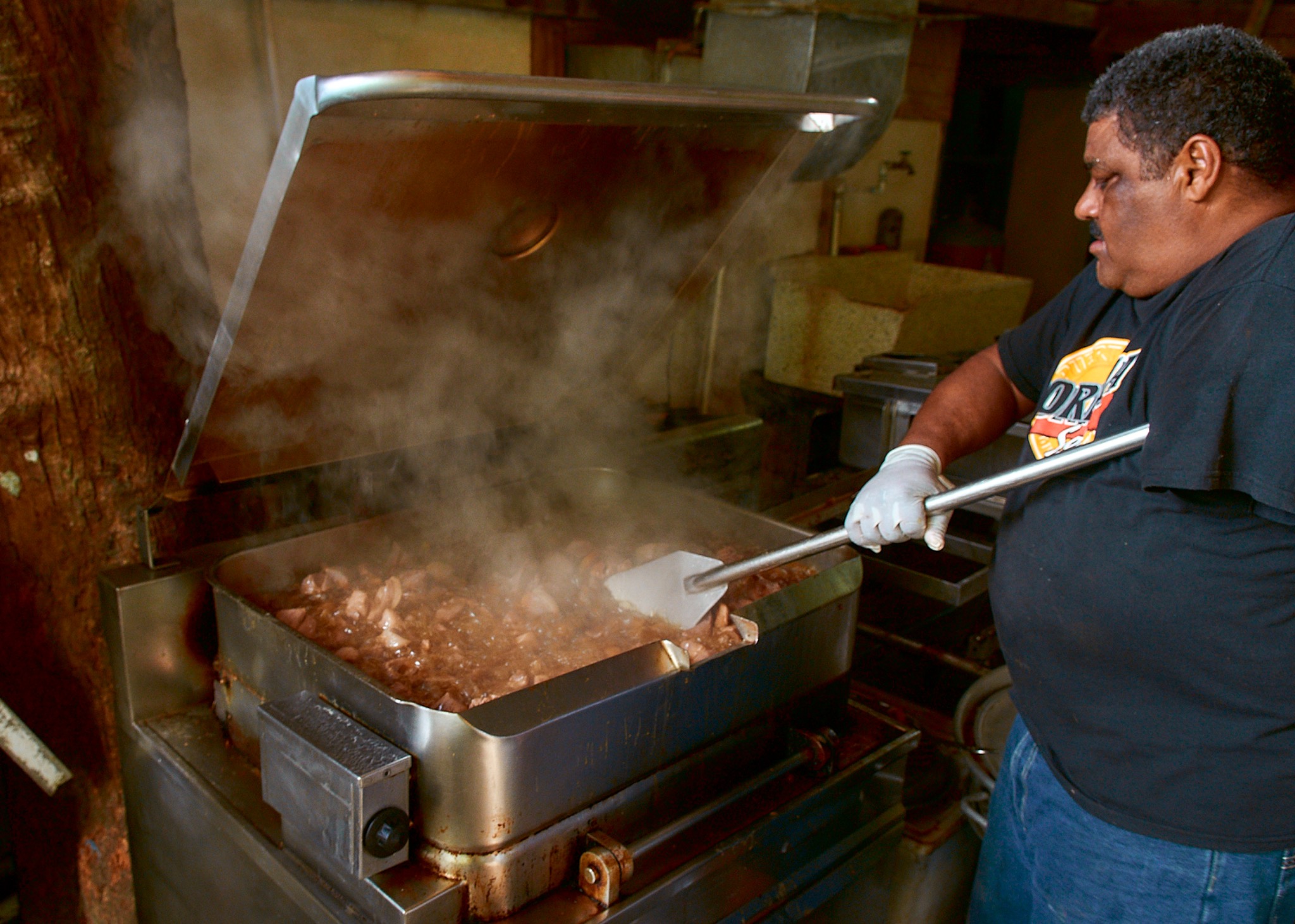 A cook preparing pork over a steaming pan in Puerto Rico.